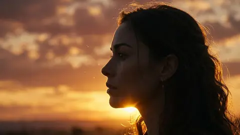 A woman in profile against a golden sunset